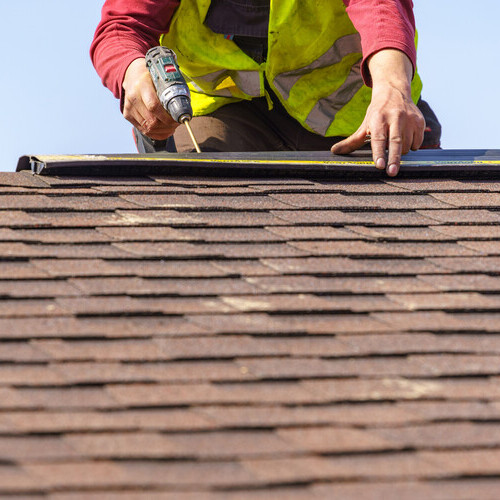 a workman repairing a shingle roof